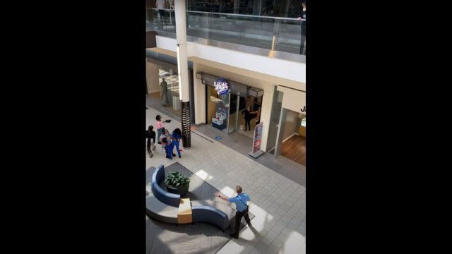 Man casually strolls past woman pointing gun inside mall