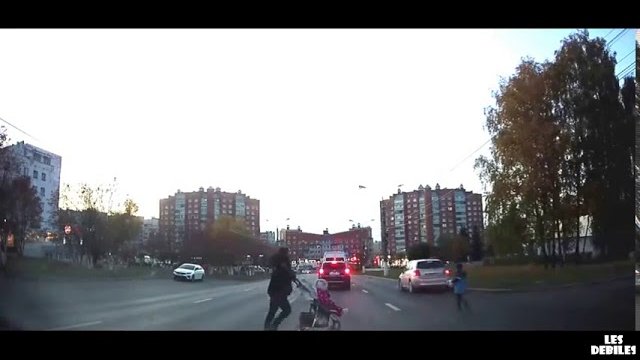 Mother of the year runs along a very busy road with her children