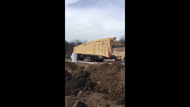 A truck unloads wooden planks