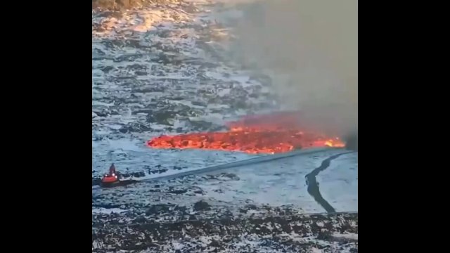 Icelandic workers trying to stop a tide of lava with an excavator, a truck and a bunch of soil