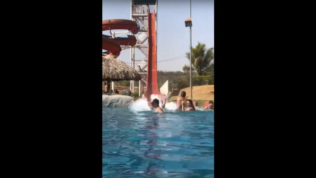 Guy on slide collides with unsuspecting swimmer