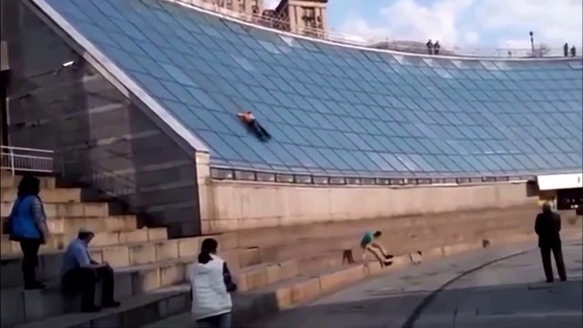 Two guys sliding down a glass building